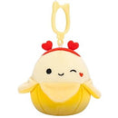 Squishmallows kulcstartós plüssfigura 9 cm - Junie a kacsintó sárga banán szivecskés fejpánttal